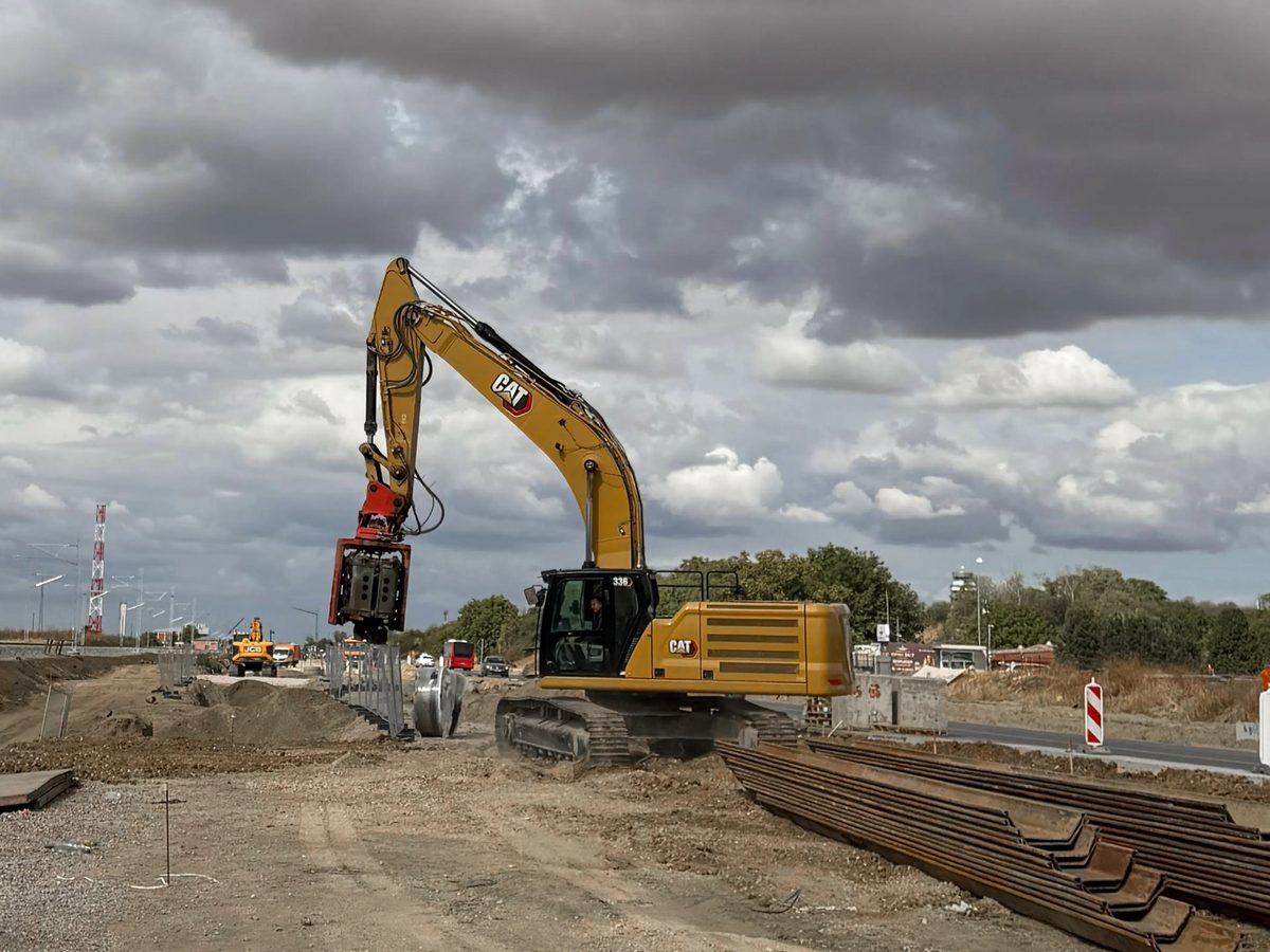 CAT 336 with a side grip vibro hammer, sheet piles stacked in the foreground